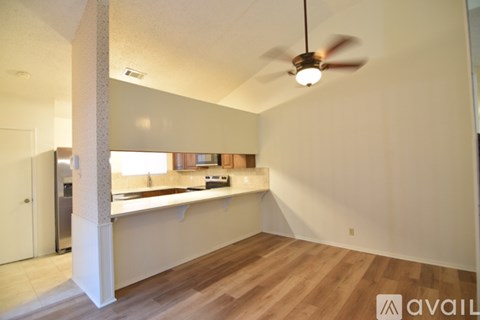 A room with a ceiling fan and a kitchen area with a sink and counter.