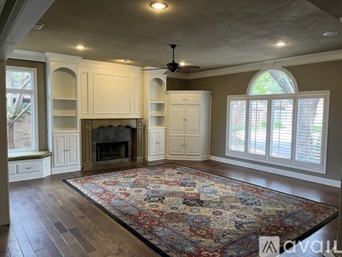 A living room with a fireplace and a rug on the floor.