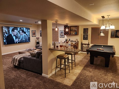 A living room with a pool table and a bar area.