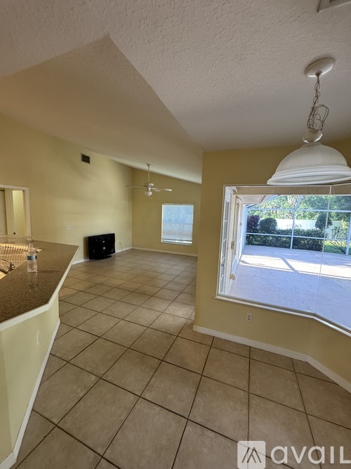 A living room with a brown tile floor and a window showing an outdoor view.