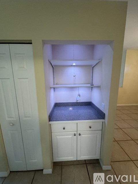 A kitchen pantry with a white door and a white cabinet with a drawer and a counter top.
