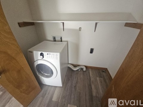 A washing machine is in a small room with wood paneling.
