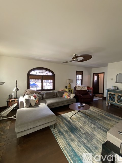 A living room with a grey couch and a rug.