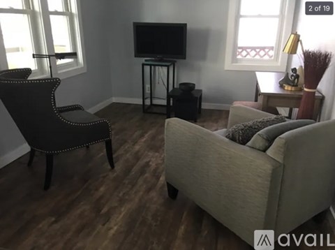 A living room with a black chair, a grey couch, and a television on a stand.