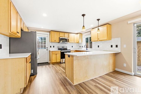 A kitchen with wooden cabinets and a black refrigerator.