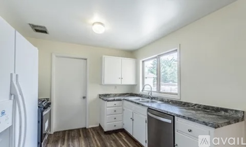 A kitchen with white cabinets and a marble countertop.