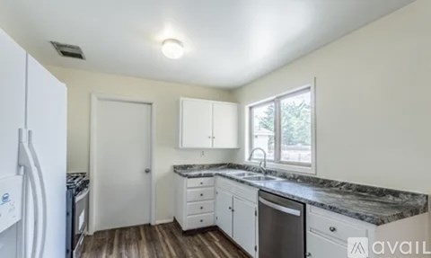 A kitchen with white cabinets and a marble countertop.