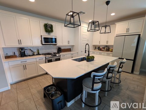 A kitchen with white cabinets and a large island with four chairs.