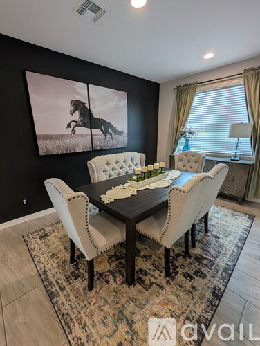 A dining room with a black table and chairs, a rug, and a large picture of a horse on the wall.