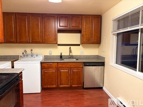 A kitchen with wooden cabinets and a white dishwasher.