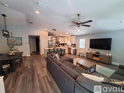 A living room with a dark brown couch and a ceiling fan.