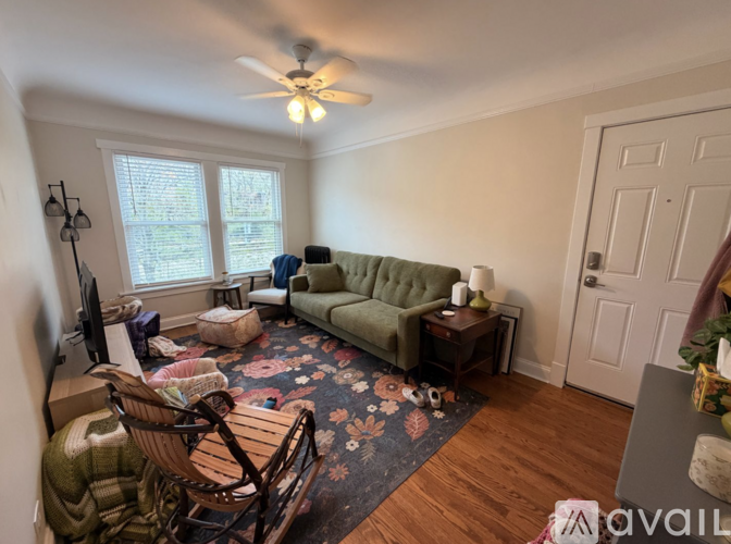 A living room with a green couch and a wooden rocking chair.