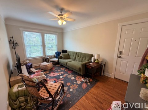 A living room with a green couch and a wooden rocking chair.