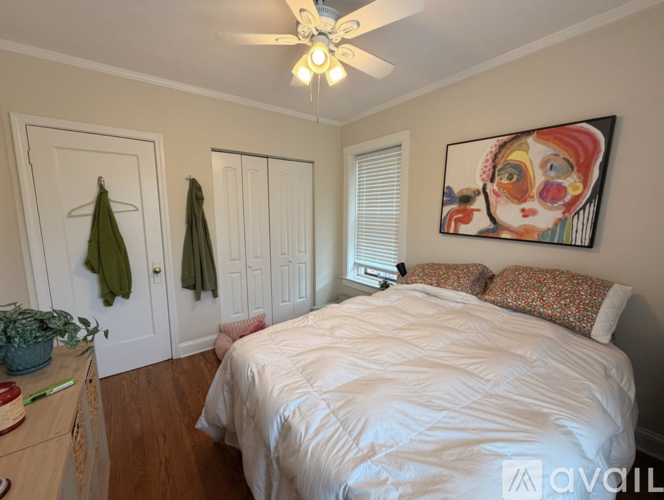 A bedroom with a large bed and a painting on the wall.