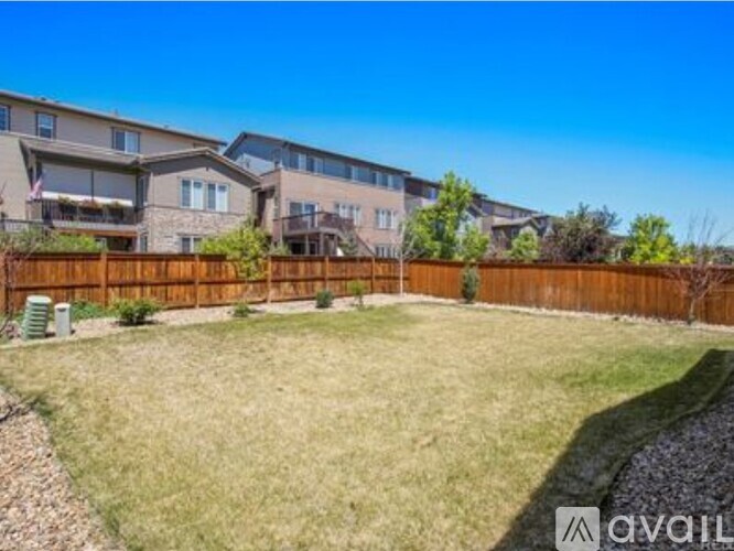 A backyard with a wooden fence and a grassy area in front of apartment buildings.