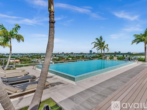 A pool surrounded by palm trees and deck chairs.