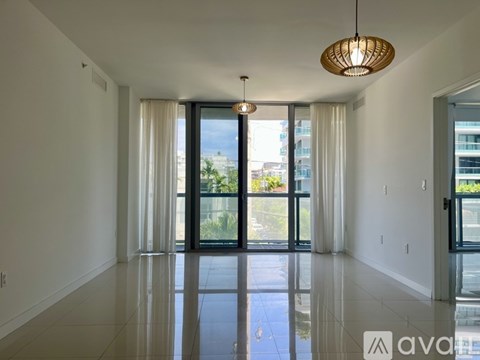 A spacious room with a large window and a hanging light fixture.