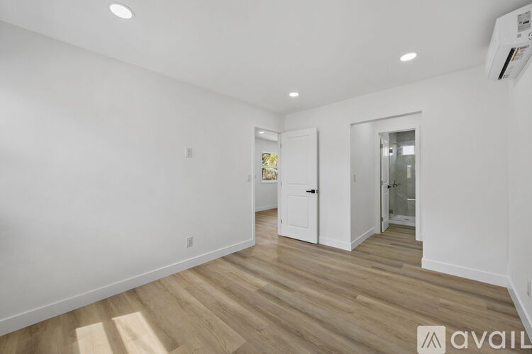A spacious room with wooden flooring and white walls.