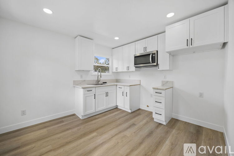A kitchen with white cabinets and a wooden floor.