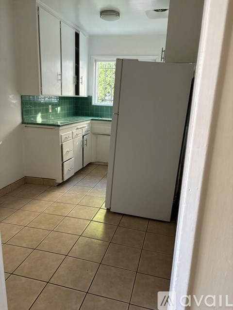 A kitchen with white cabinets and a green backsplash.