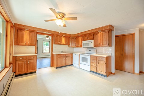 A kitchen with wooden cabinets and a white ceiling fan.