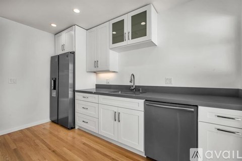 A modern kitchen with white cabinets and a dark countertop.