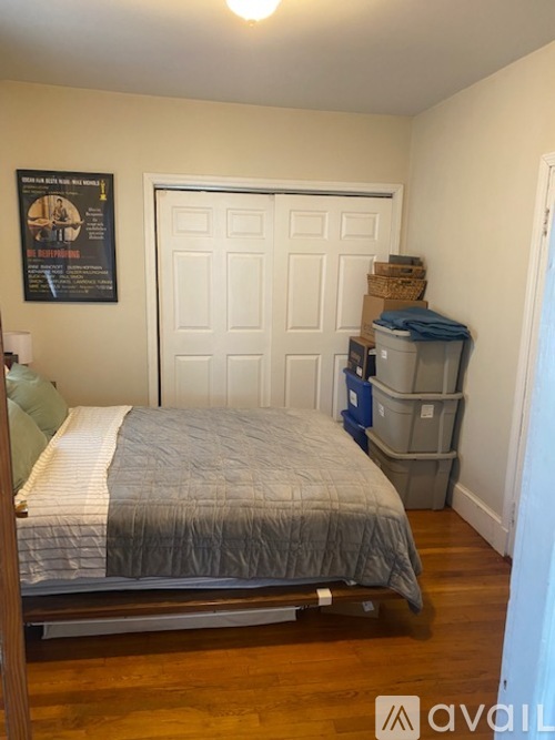 A bedroom with a bed, a poster, and a white door.