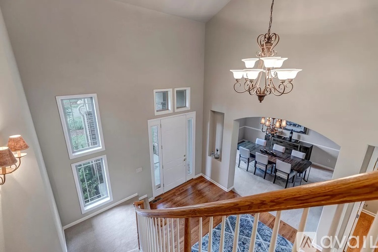 A chandelier hangs in a spacious room with a dining table and chairs.