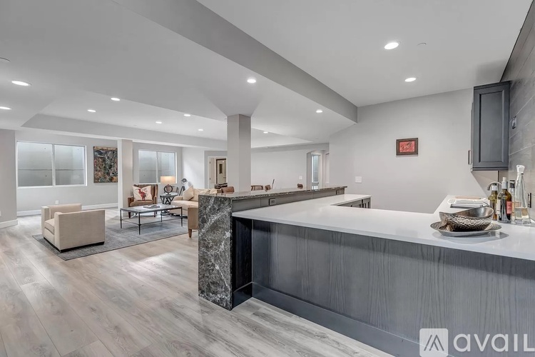 A modern kitchen with a marble island and a dining area with a table set for two.