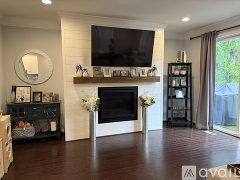 A living room with a fireplace and a television mounted above it.