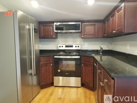 A kitchen with wooden cabinets and a stainless steel refrigerator.