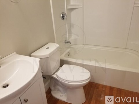 A white toilet sits next to a white sink in a small bathroom.