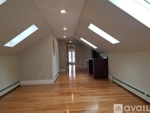 A spacious room with wooden floors and skylights.
