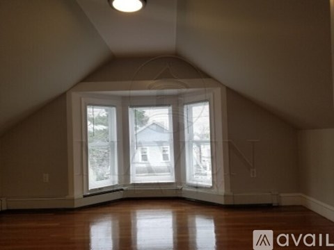 A room with a large window and wooden floors.