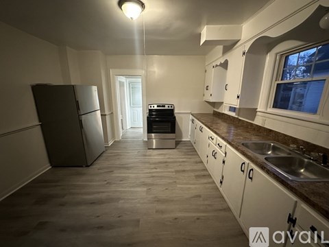 A kitchen with a black fridge and a black stove top oven.