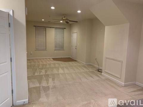 A room with a carpeted floor and a ceiling fan.