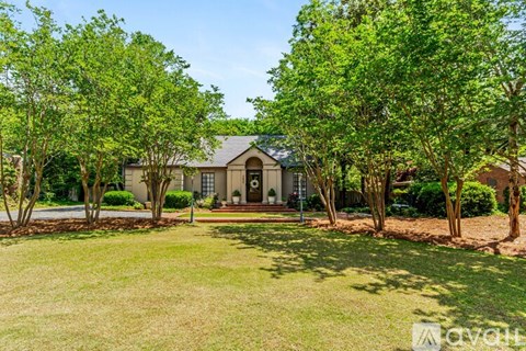 A house with a lawn and trees in front of it.