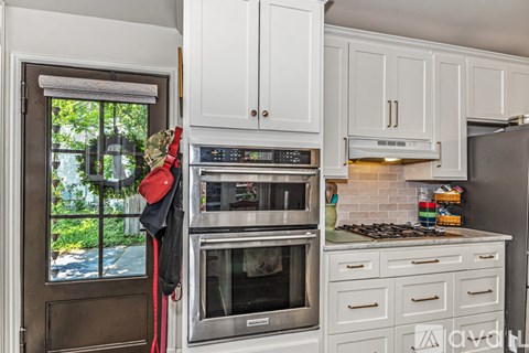 A modern kitchen with white cabinets and stainless steel appliances.