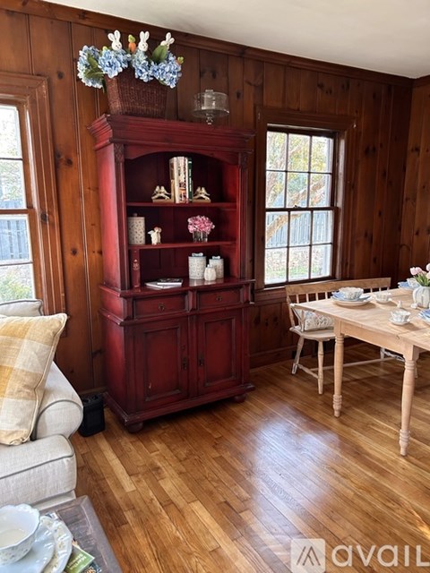 A wooden floor in a room with a red cabinet and a table.