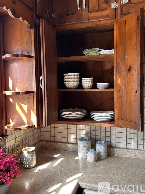 A kitchen with a wooden cabinet and a lit candle inside.