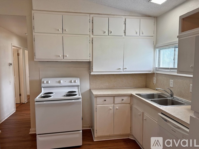 A kitchen with white cabinets and a white stove.