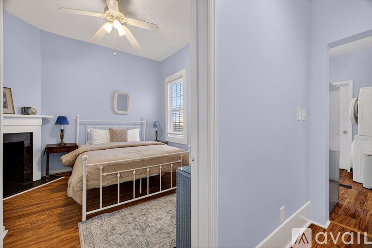 A bedroom with a bed, a fireplace, and a ceiling fan.