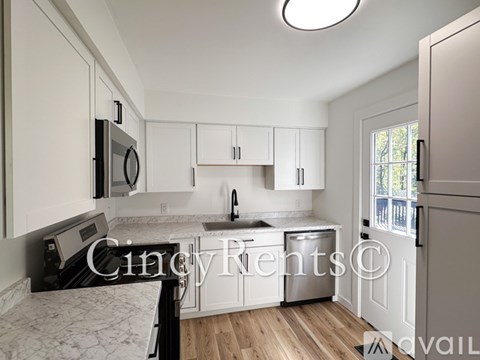 A kitchen with white cabinets and a wooden floor.