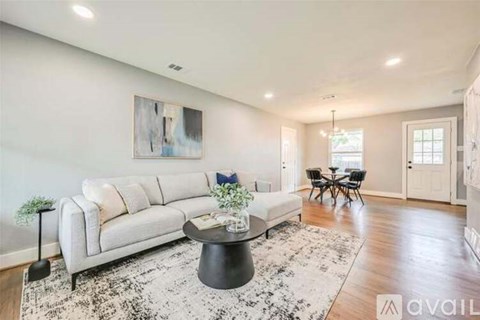 A living room with a white sofa, a coffee table, and a painting on the wall.