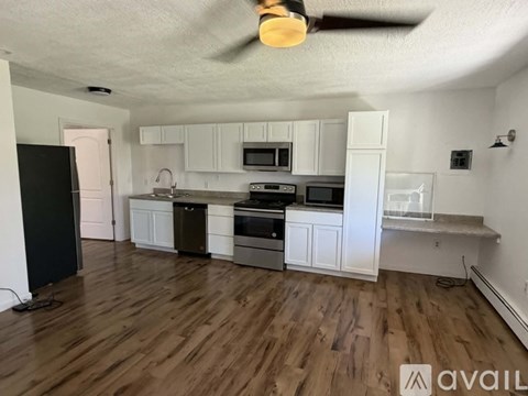 A kitchen with white cabinets and a black refrigerator.