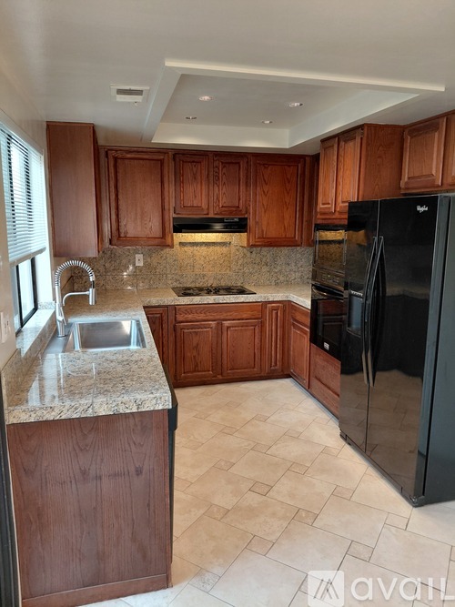 A kitchen with wooden cabinets and a black refrigerator.