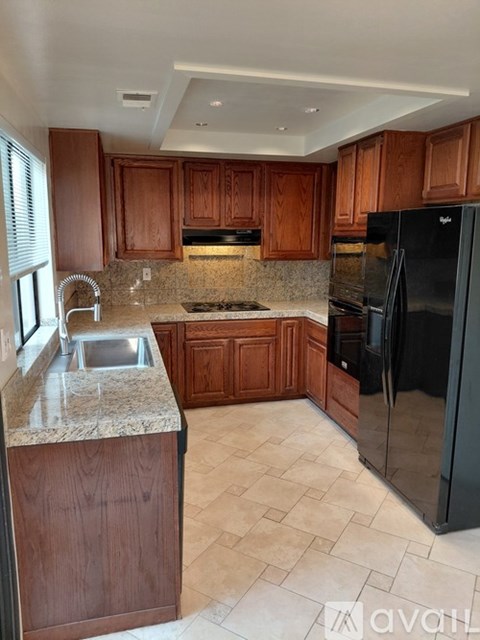 A kitchen with wooden cabinets and a black refrigerator.