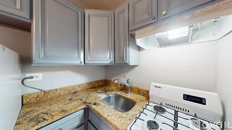 A kitchen with a granite countertop and a white stove top oven.
