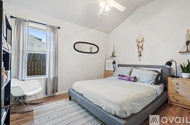 A bedroom with a bed, chair, and a window with curtains.