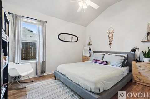 A bedroom with a bed, chair, and a window with curtains.